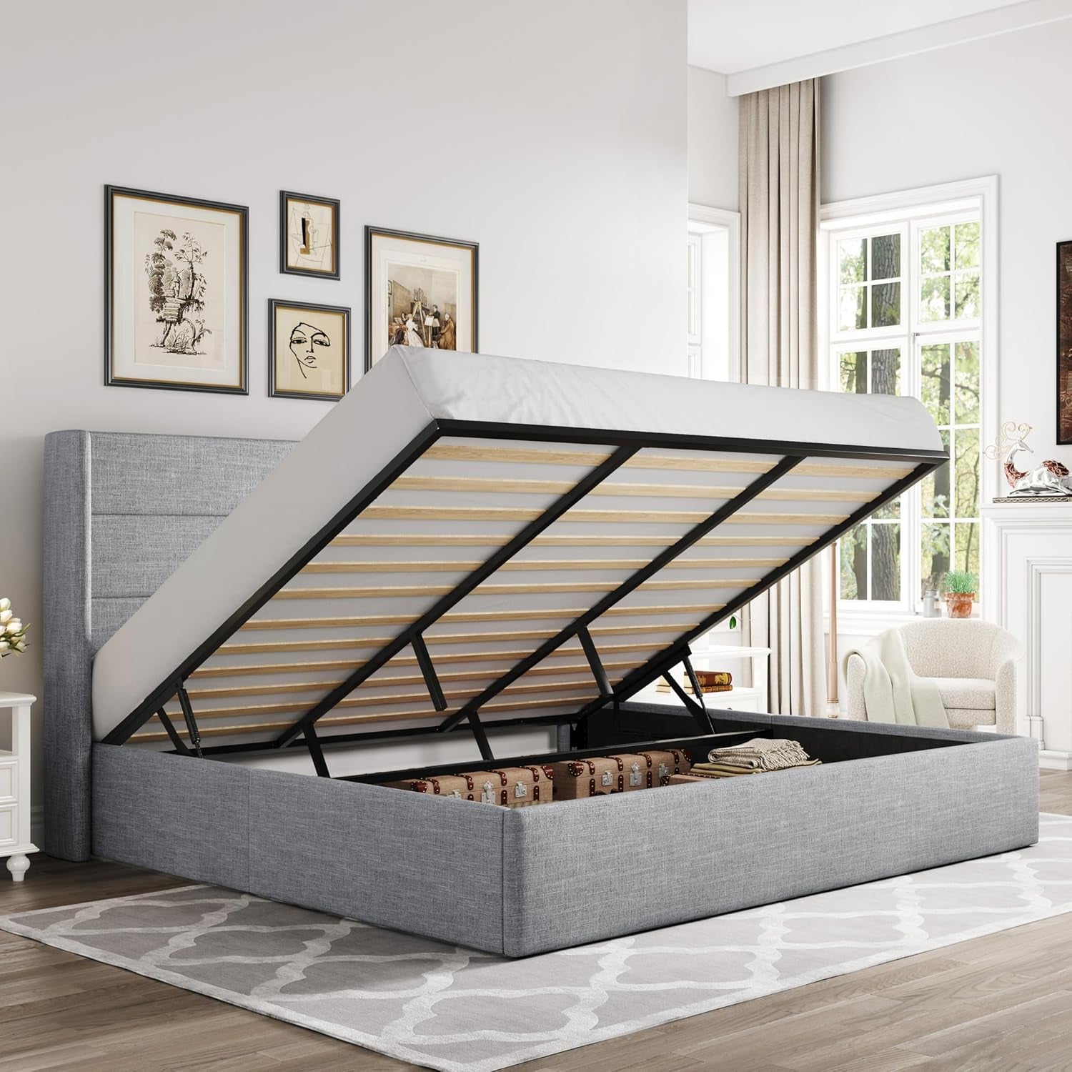 Gray fabric storage bed with mattress lifted to show internal storage compartment in a styled bedroom.
