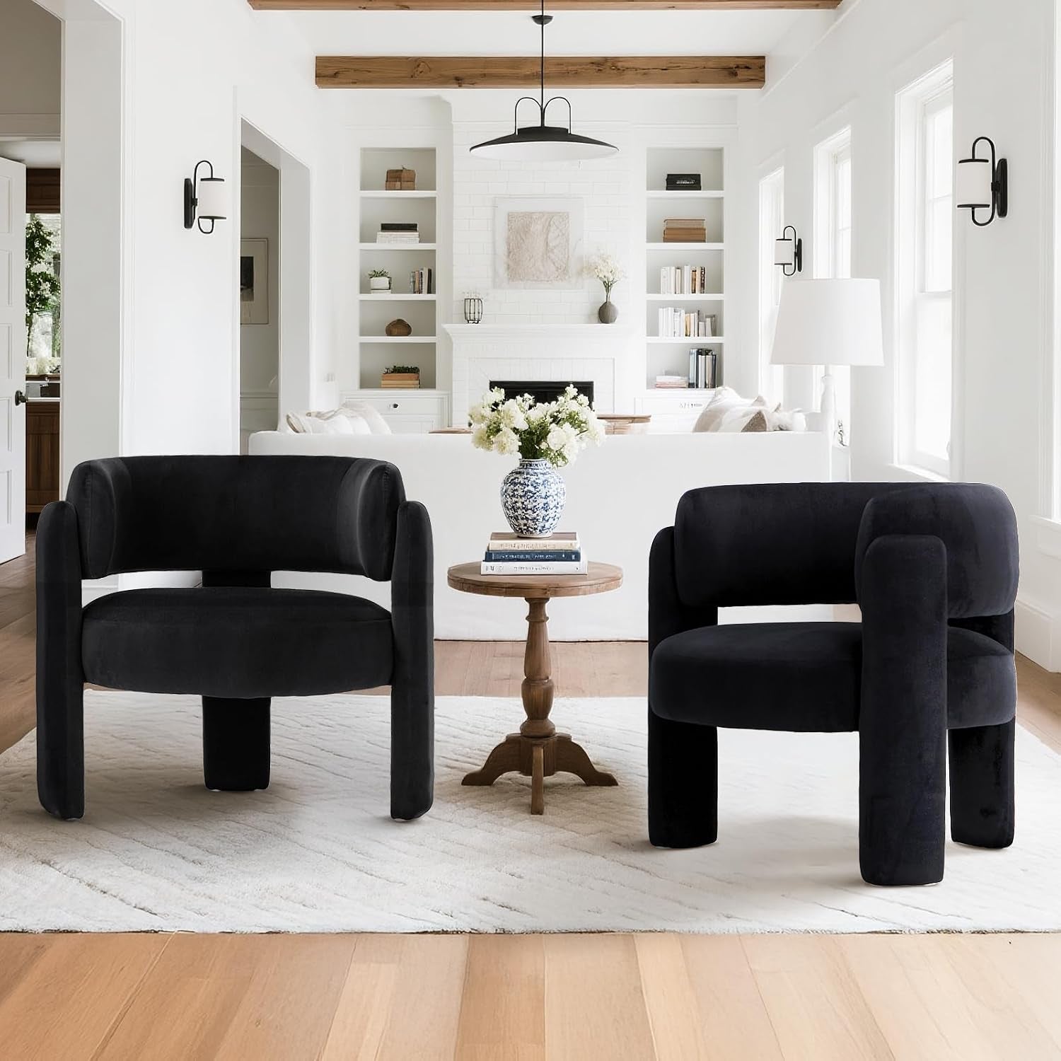 Pair of low barrel chairs in dark velvet flanking a small round wood table in a bright white living room