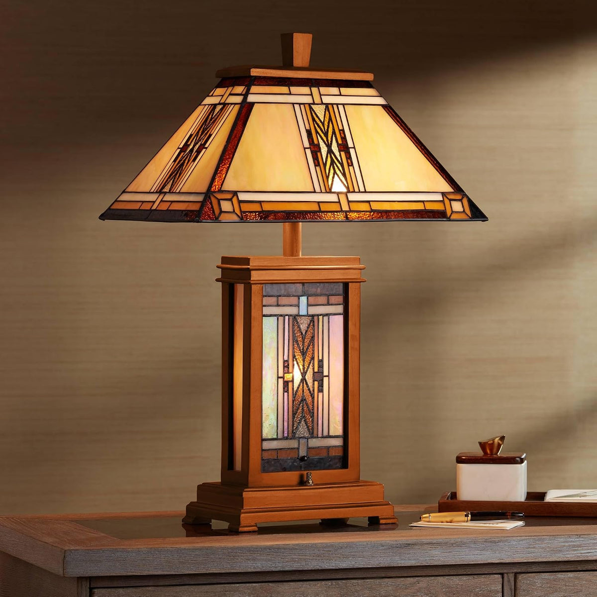 Full lit lamp on a table showing stained-glass shade and rectangular wood base, ambient room setting