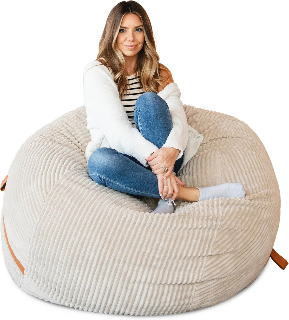 Front view of a woman seated cross-legged in the center of a ribbed beige lounger on a white background.
