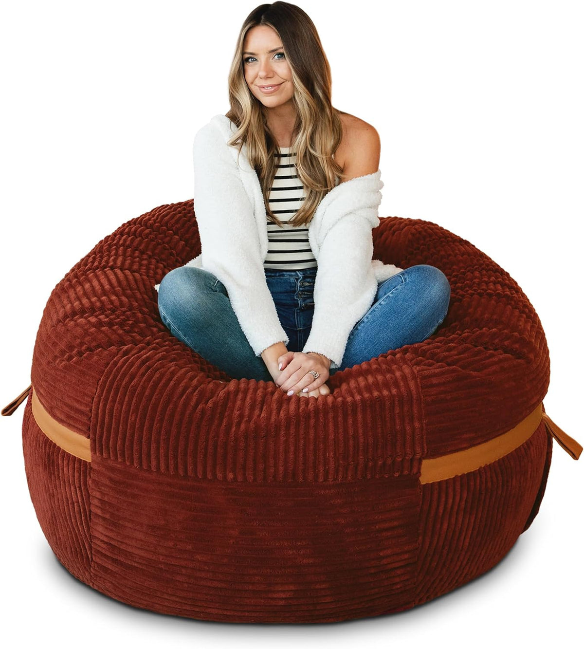 Woman seated cross-legged in a large rust-red ribbed lounger with visible tan carry strap.