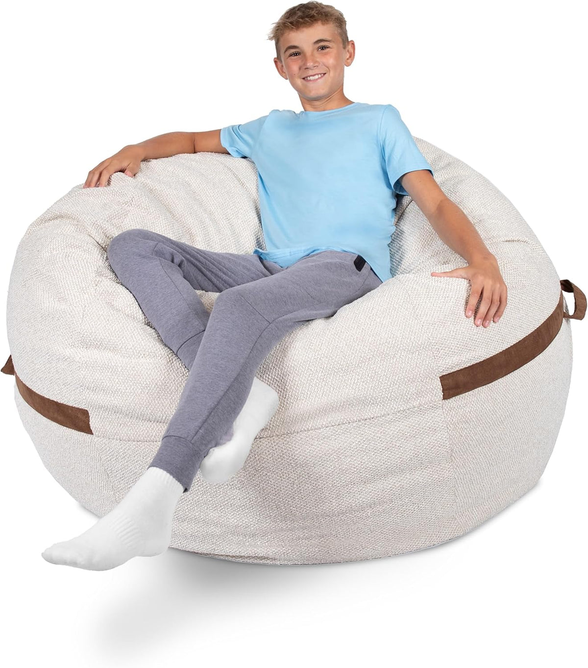Teen boy reclined on a textured off-white oversized bean bag with brown fabric handles.