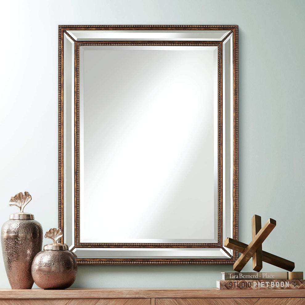 Rectangular mirror with mottled bronze beaded frame shown hanging above a wooden console with decorative jars