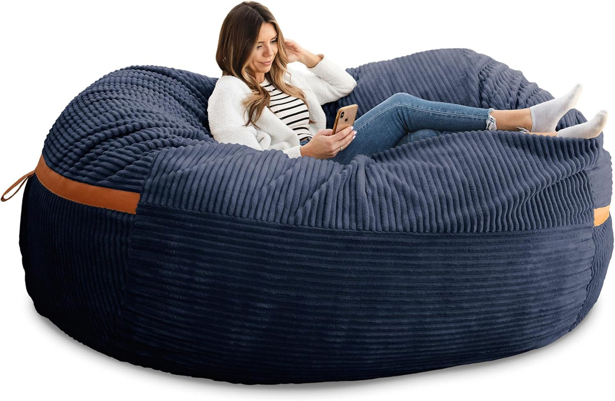 Angled view of a navy ribbed oversized lounger with a woman reclining and looking at her phone