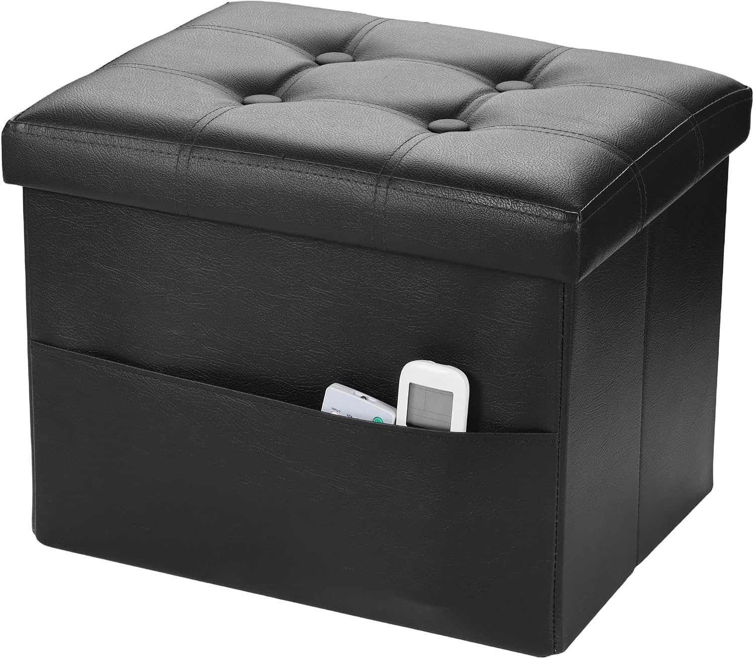 Black faux-leather folding storage ottoman with tufted lid and front pocket holding two remotes