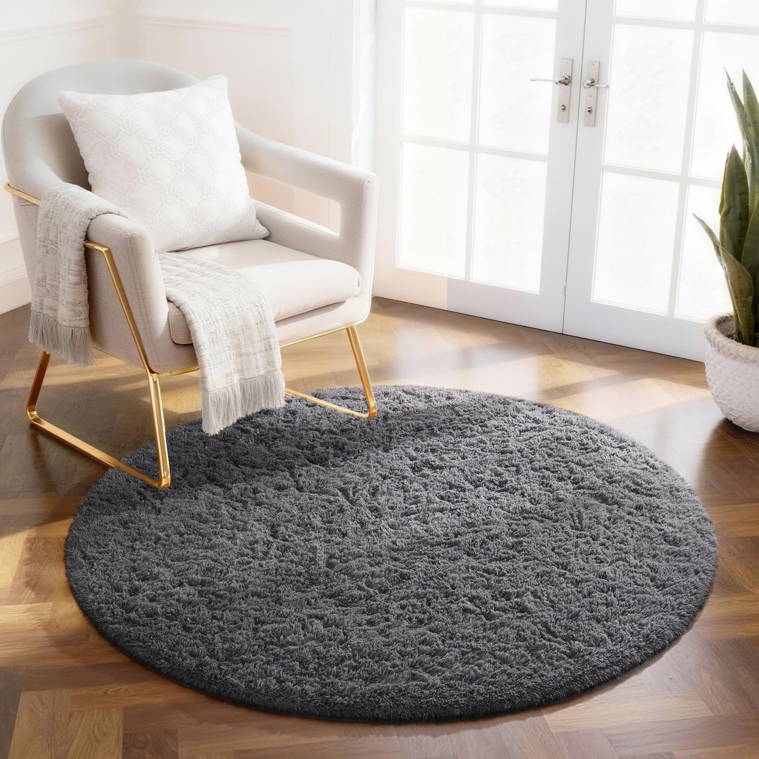 Round dark gray shag rug on parquet floor under a modern armchair by French doors