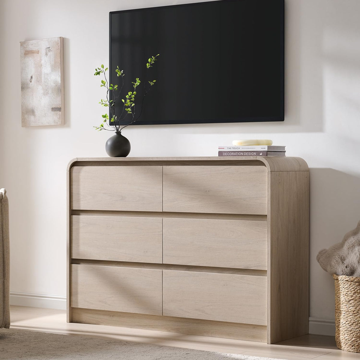Wide light oak dresser with rounded top corners and three stacked drawer rows beneath a wall-mounted TV.