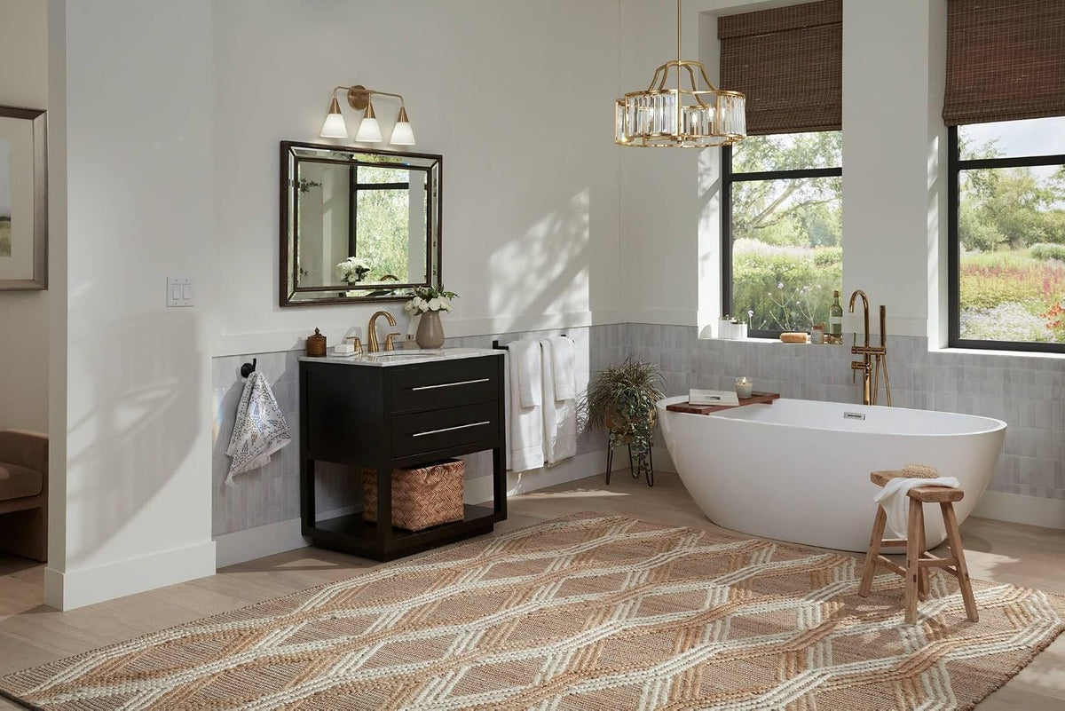 Wide bathroom scene showing the beaded bronze rectangular mirror above a dark vanity, freestanding tub, and woven rug.