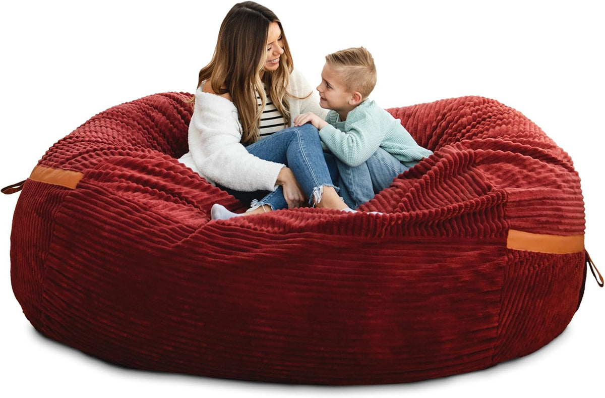Woman and child sitting together in the center of a large ribbed red bean bag lounger.
