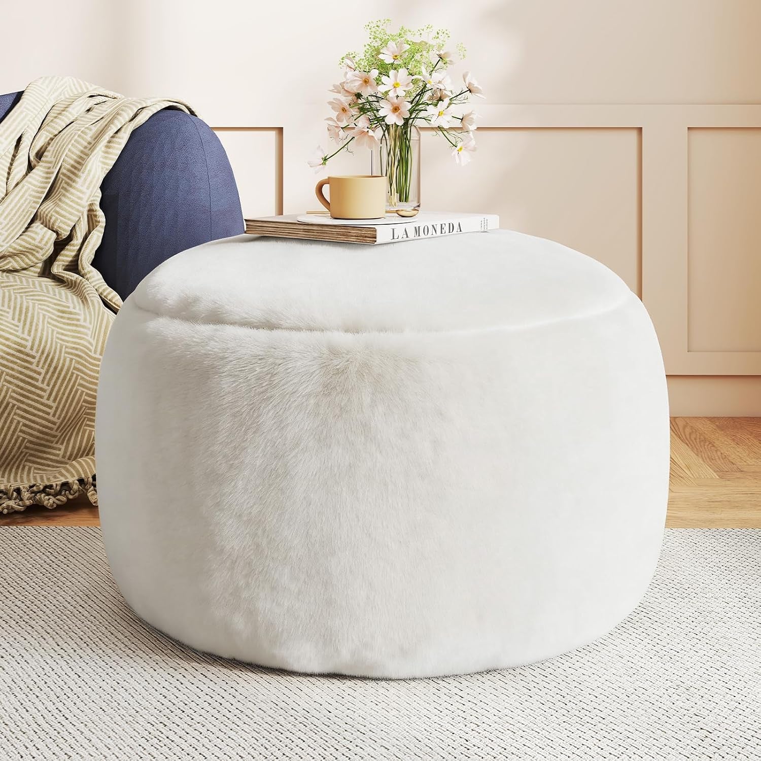 Soft pink faux-fur round pouf ottoman front view with book and vase on top