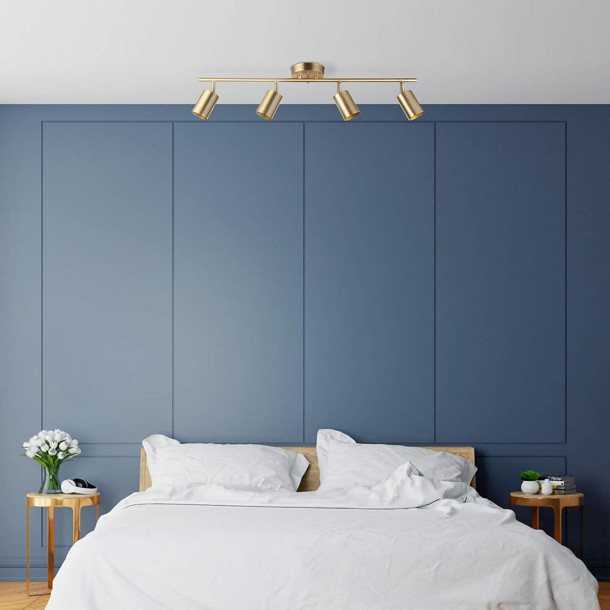 Matte brass track light installed on a ceiling above a bed with a blue accent wall, angled bedroom view