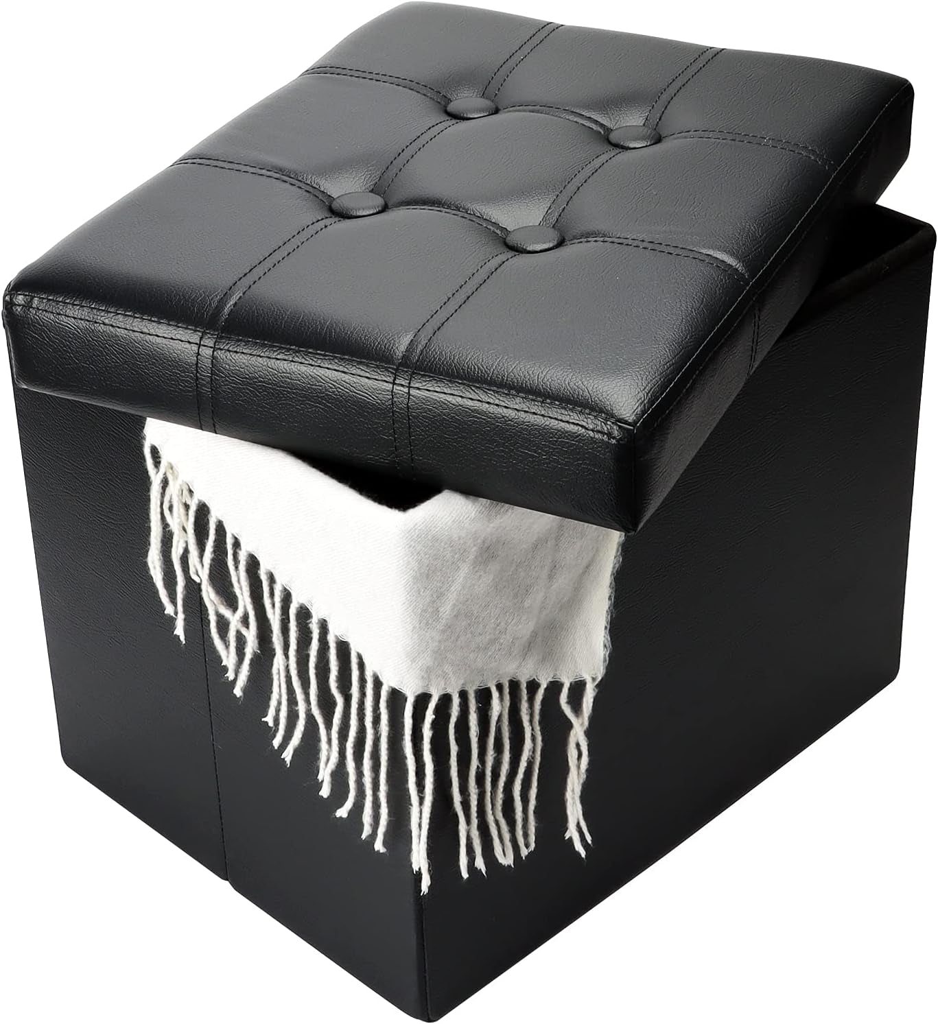 Close-up of a black tufted faux-leather storage ottoman with the lid tilted open and a white fringed throw hanging out.