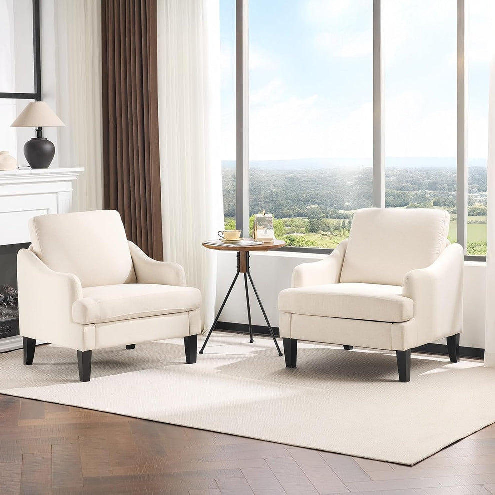 Two beige linen armchairs arranged in a bright living room angled front view with small round side table