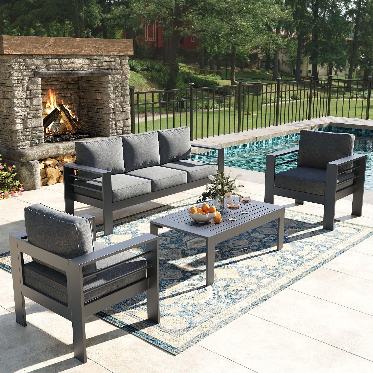 Gray metal-framed sofa and chairs grouped around a low gray slatted coffee table on an outdoor rug
