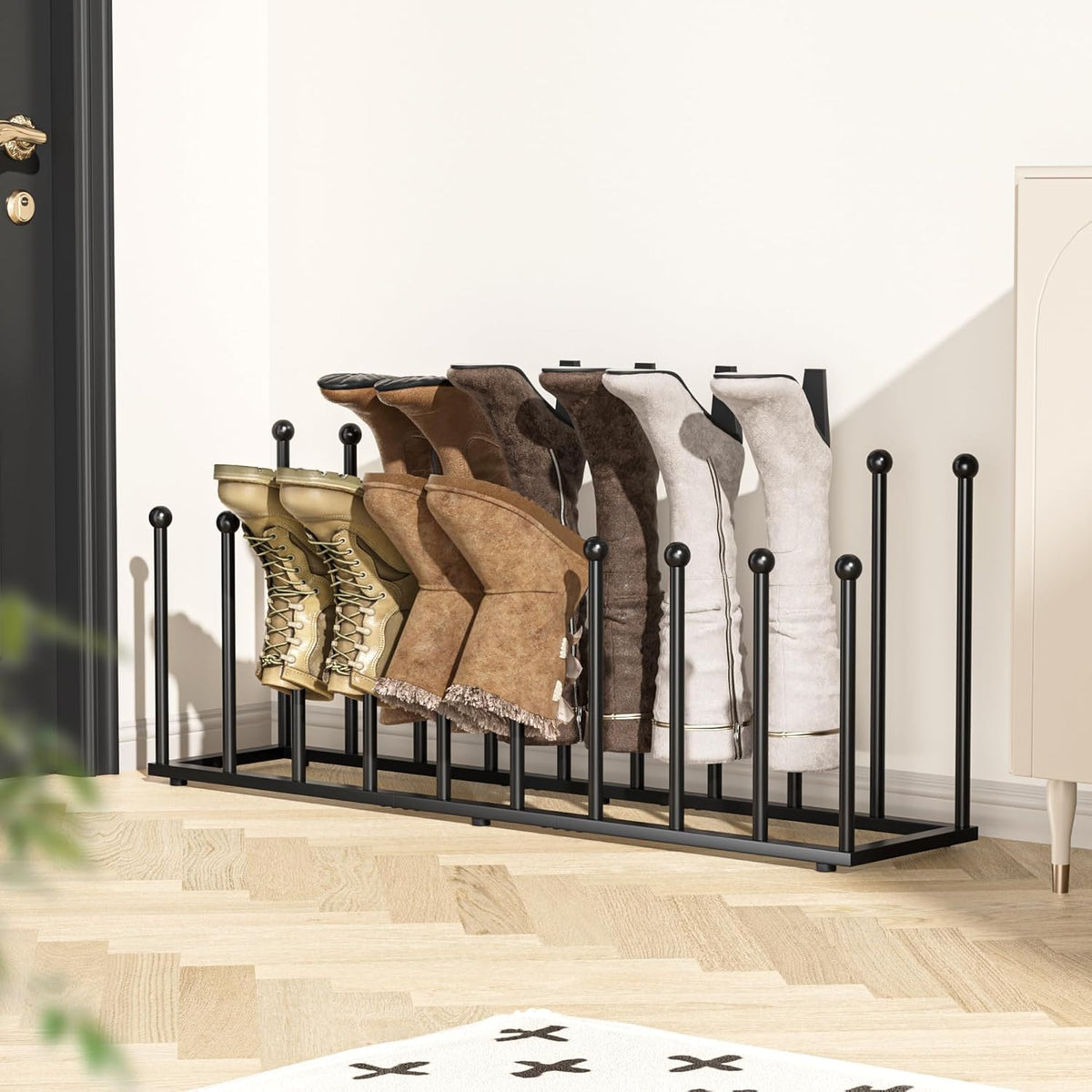 Low-angle entryway scene of the black boot rack filled with boots next to a door and rug