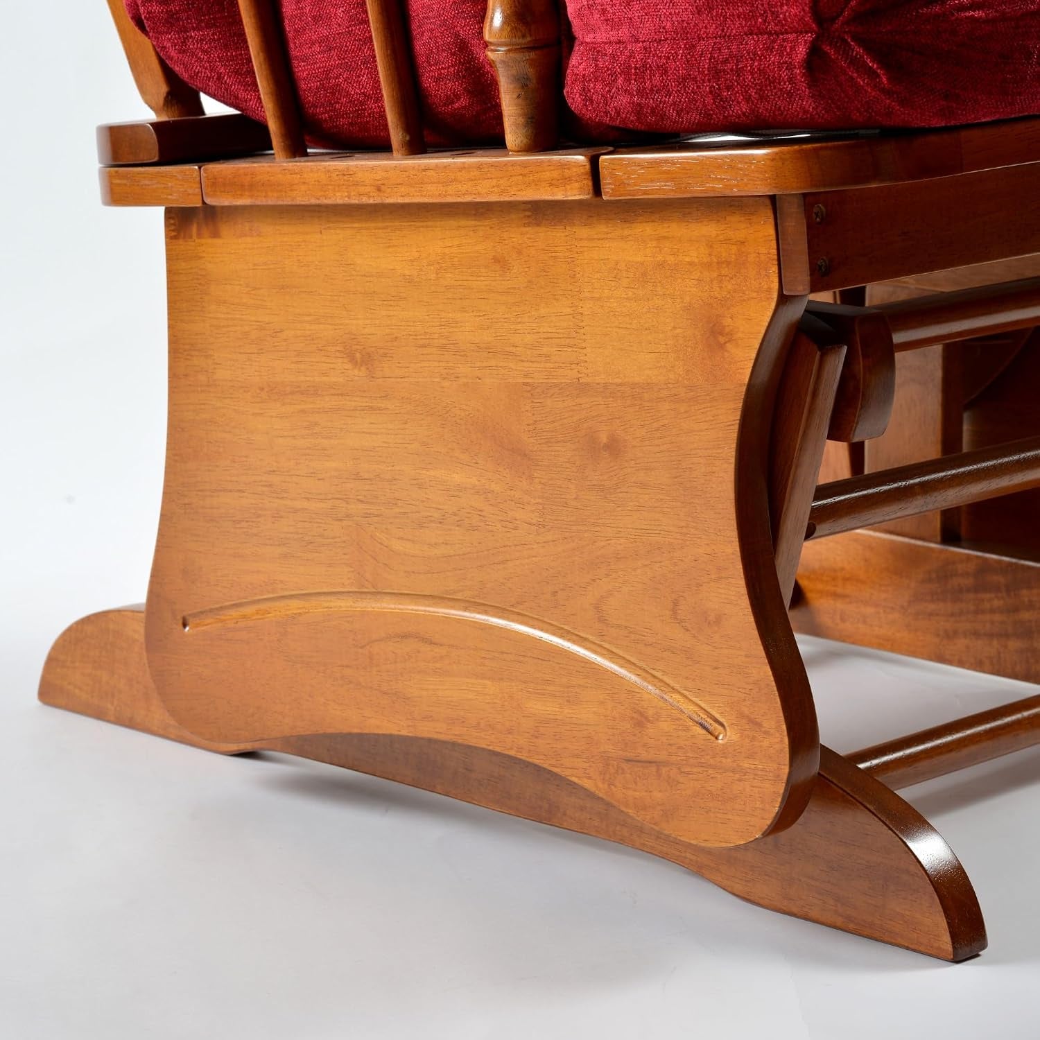 Close-up of the glider's curved wooden base and carved accent on oak-finish rocker frame.
