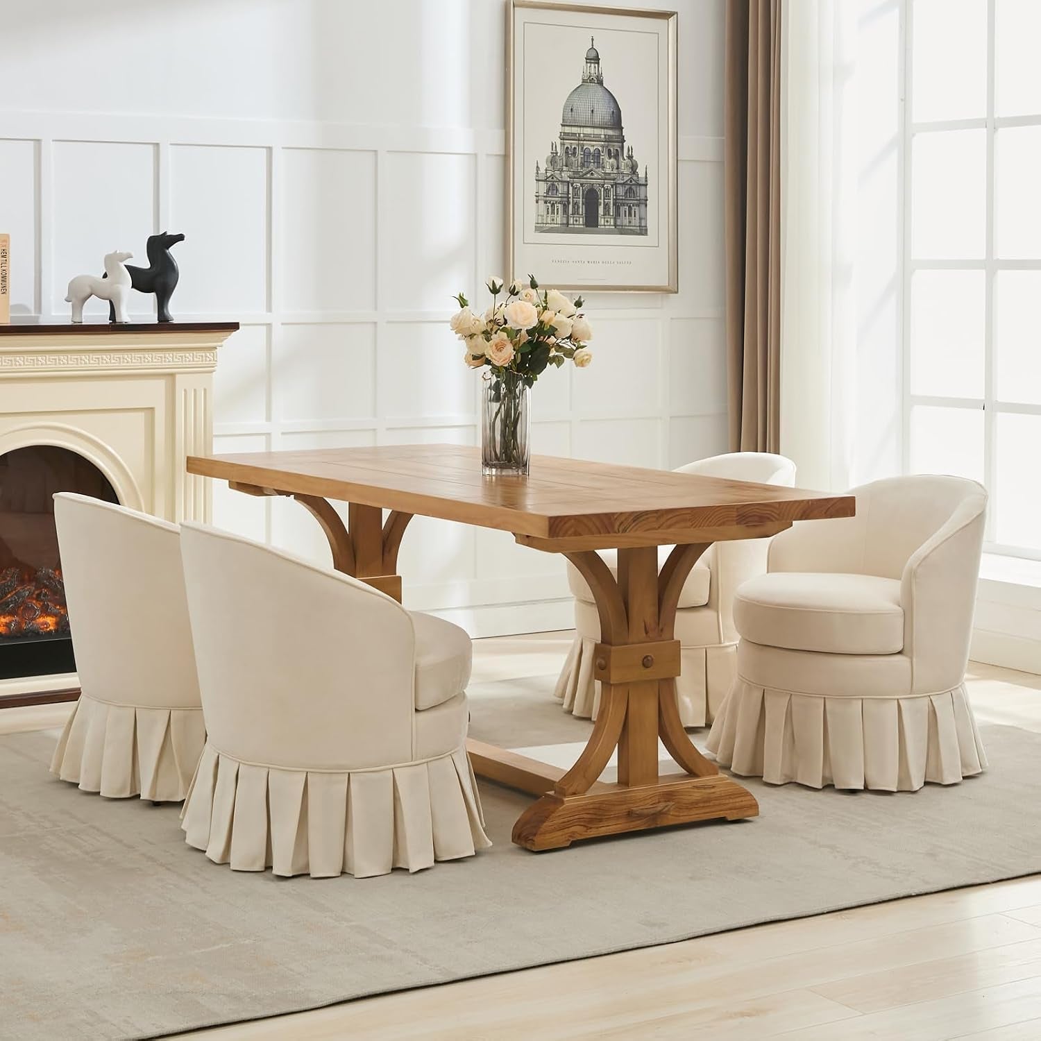 Dining room with a wooden table surrounded by four cream upholstered barrel chairs with pleated skirts.