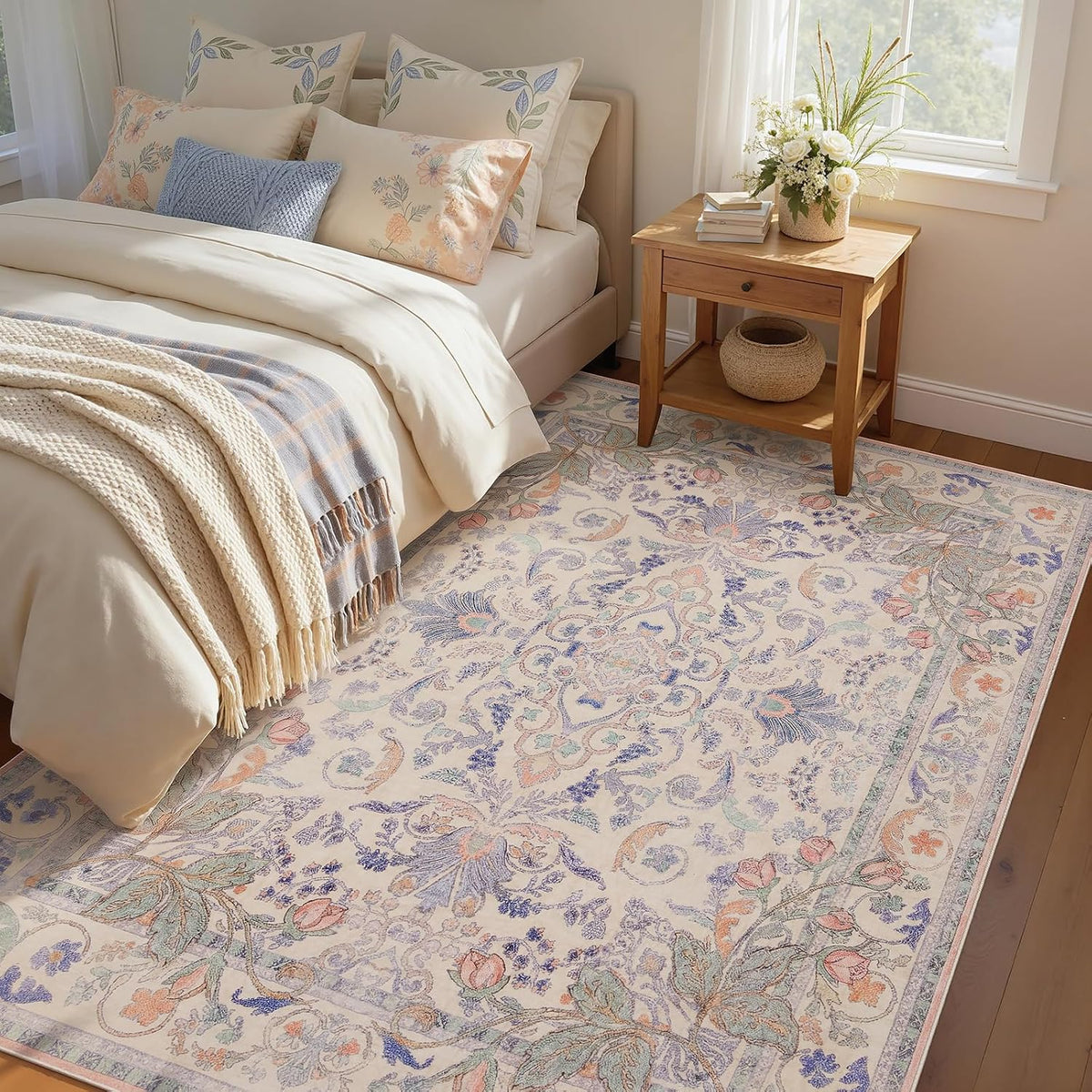 Light pastel floral rug beside a bed with cream bedding and a wooden nightstand