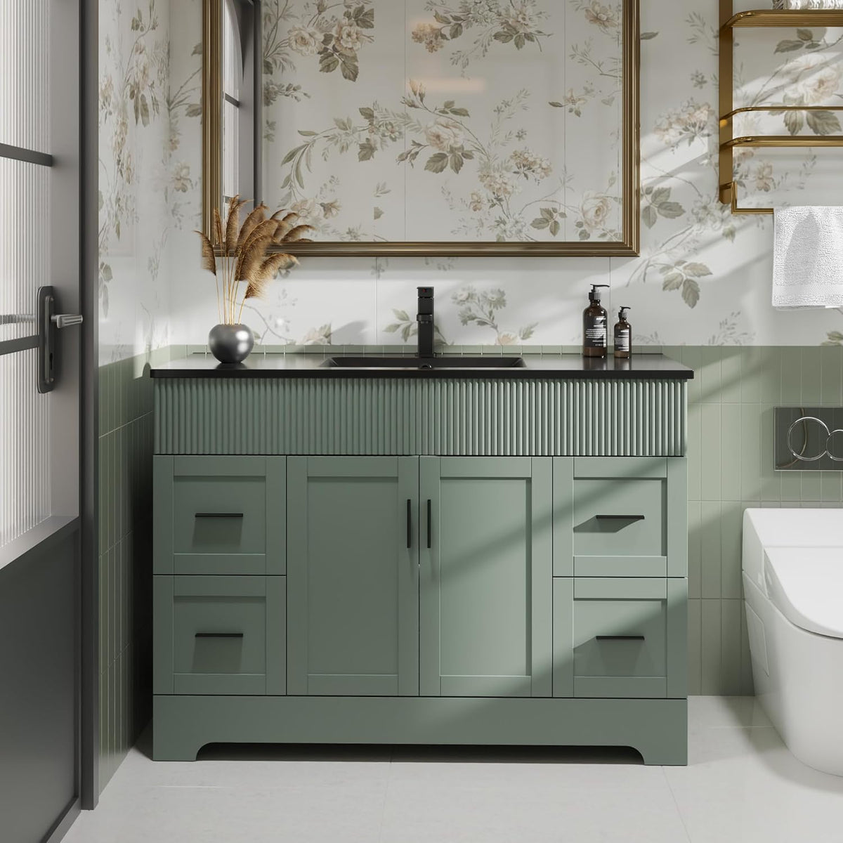 Single-sink green vanity with fluted top apron, black countertop and floral wallpaper behind