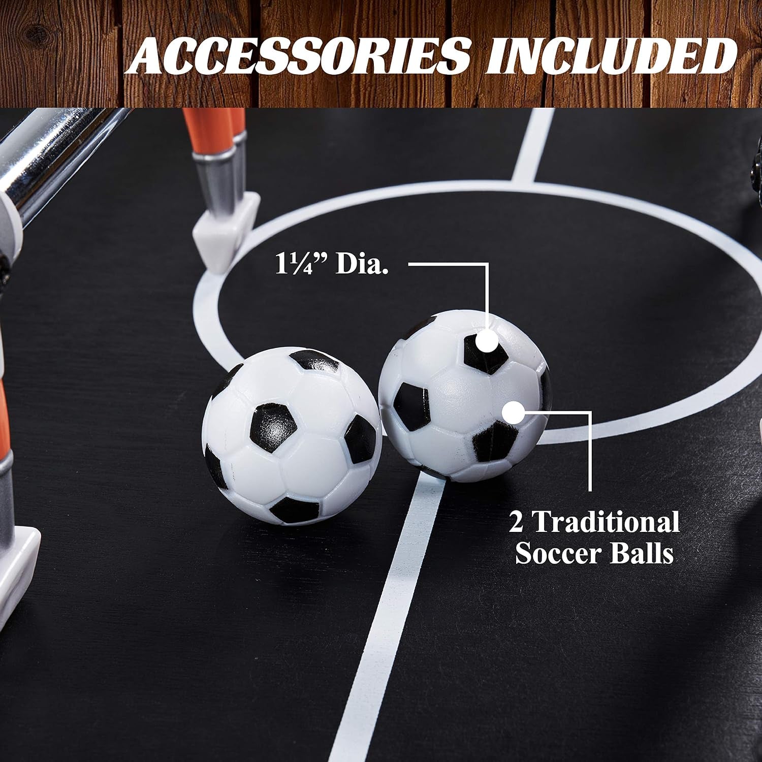 Two small black-and-white soccer balls resting on the black playing surface near the center circle and player legs.