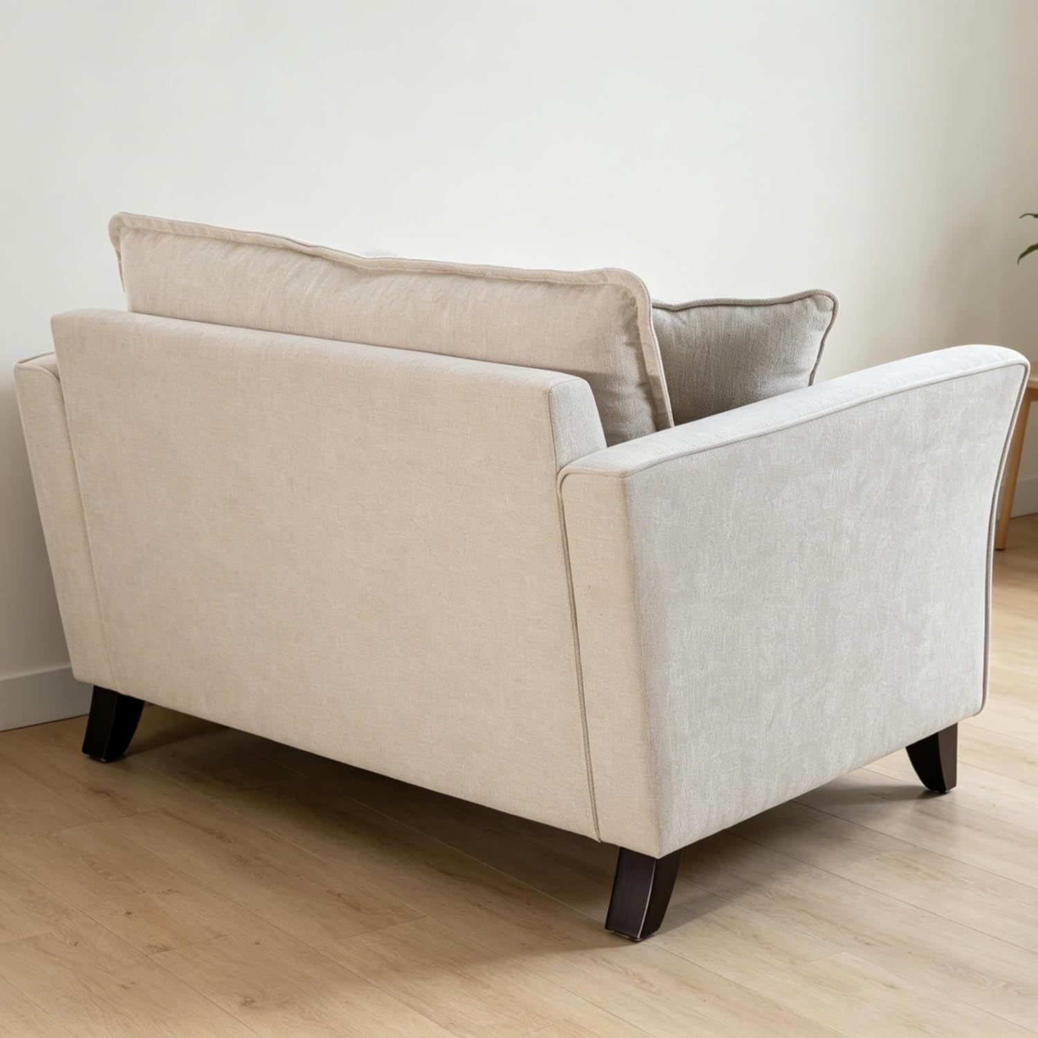Rear three-quarter view of a light beige oversized accent chair on wood floor