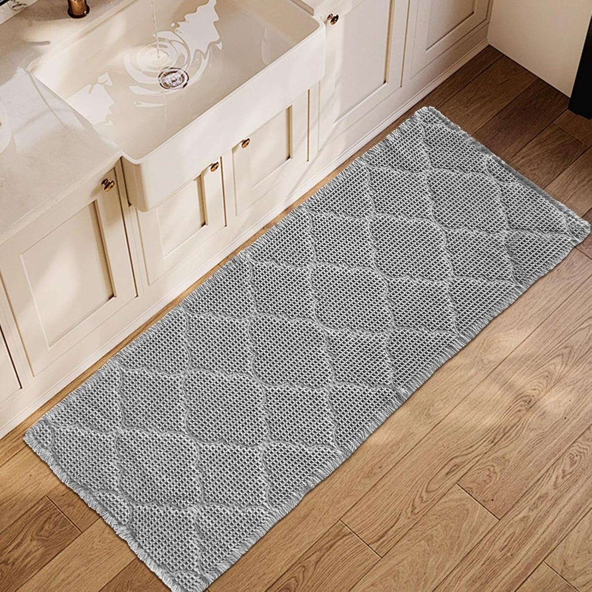 Top-down view of a light gray waffle runner laid along a bathroom vanity on wood floor.