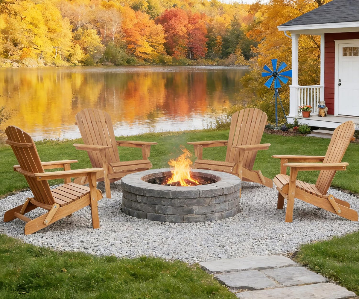 Four natural wood Adirondack chairs arranged around a stone fire pit by a lakeside with autumn foliage in the background.