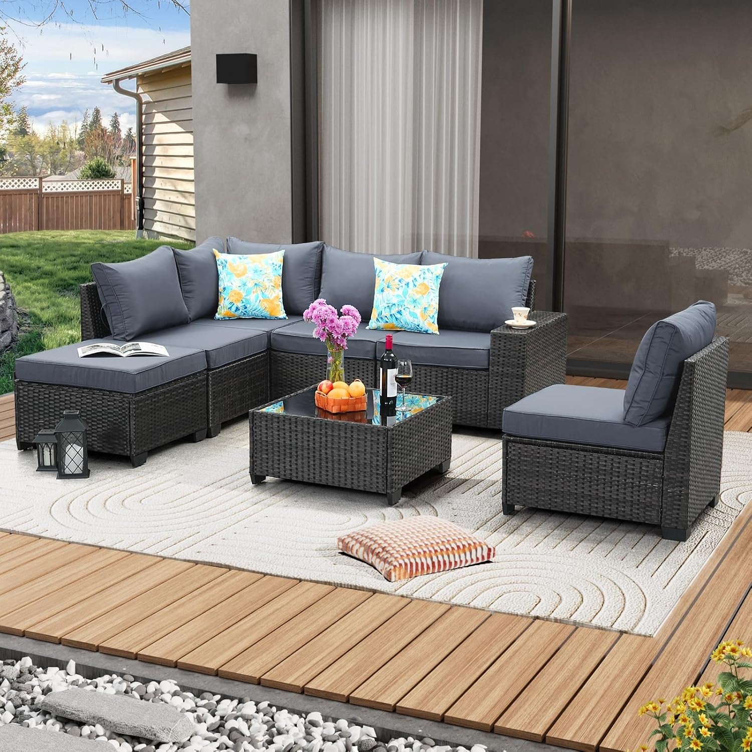Outdoor rattan sectional with medium gray cushions and separate armless chair beside a glass-top coffee table.
