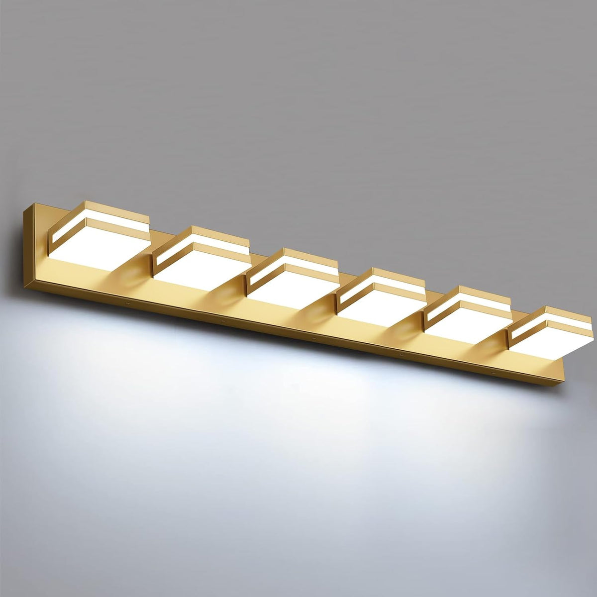 Angled view of a six-light rectangular LED vanity fixture in warm gold finish glowing against a gray background.