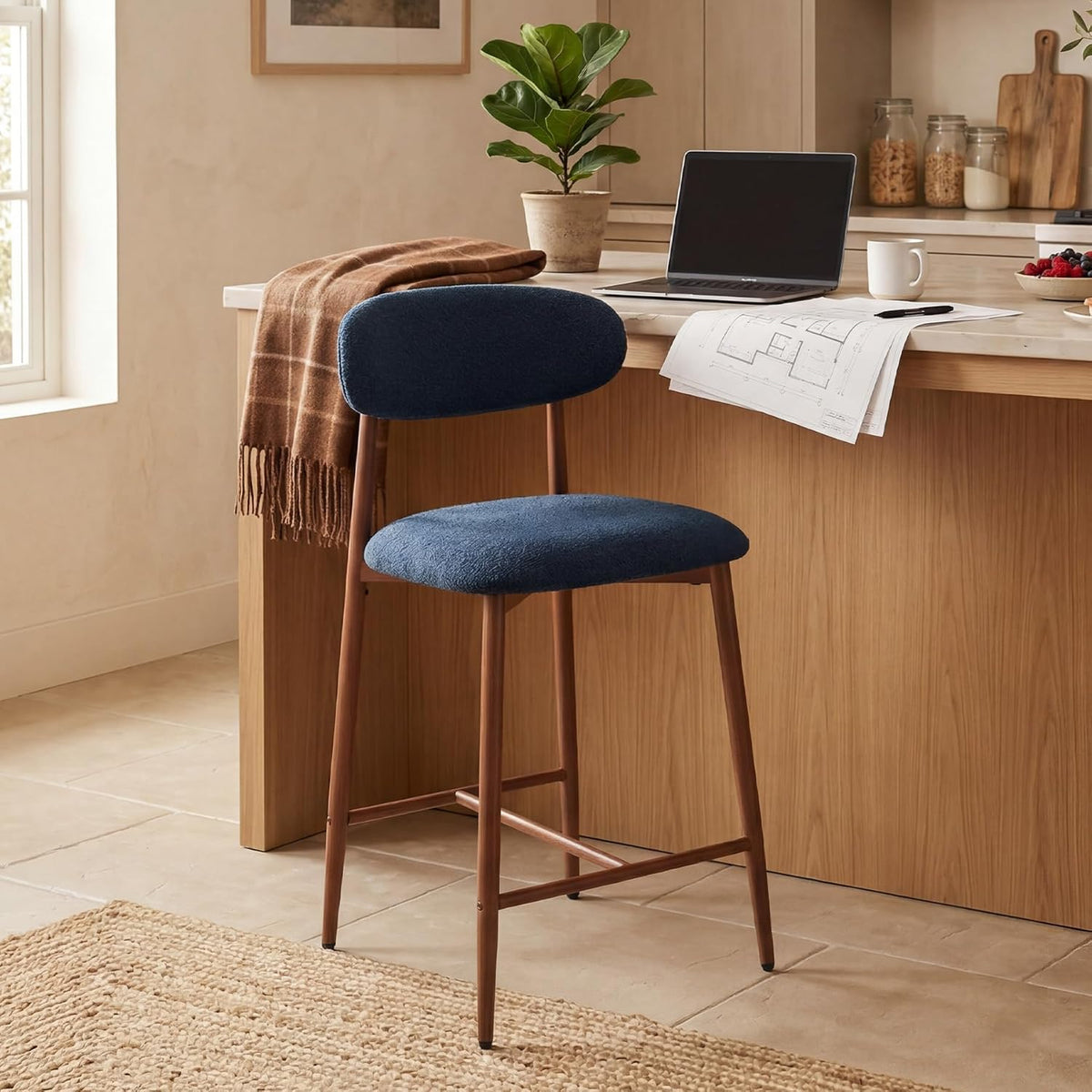 Single navy-upholstered counter stool at a kitchen island with wooden legs.