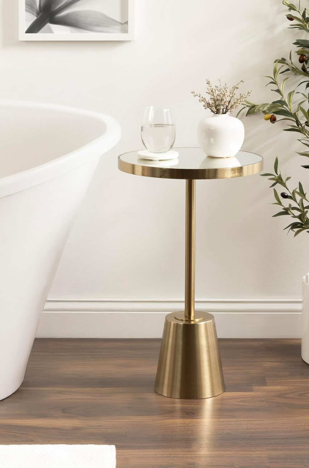 Gold mirrored side table used as a bathroom accent next to a freestanding tub on wood-look flooring