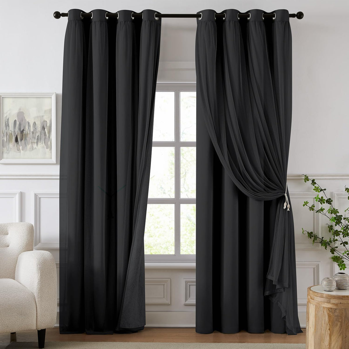 Floor-length black blackout curtains with sheer overlay tied to one side over a window in a living room.