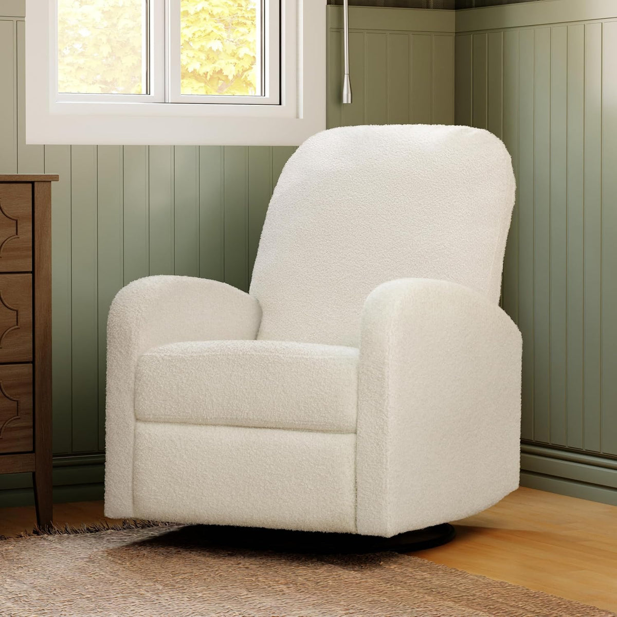 Cream boucle swivel recliner placed in a cozy corner with green wainscoting and wooden floor.
