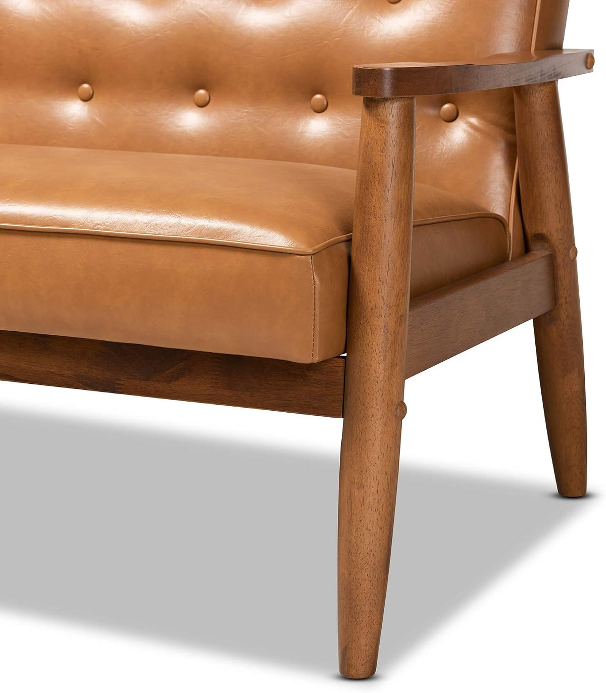 Detail of tan seat cushion with walnut armrest and tapered wooden leg showing dowel joint.