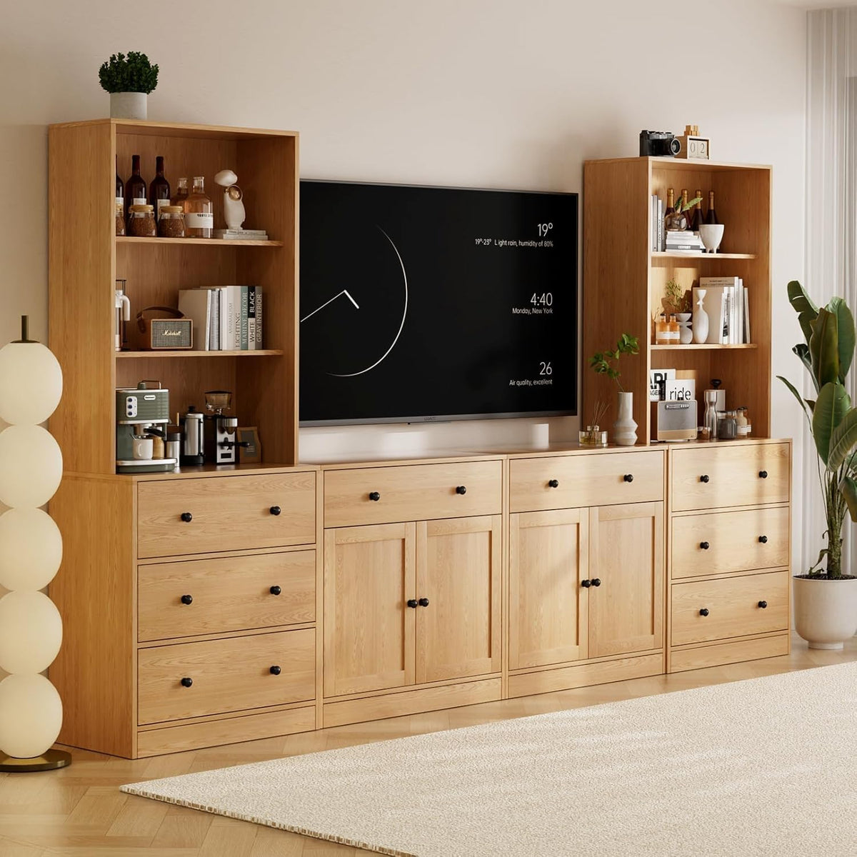 Light natural-wood modular TV stand and tall bookcases around a wall-mounted TV, accessorized with plants and tableware.