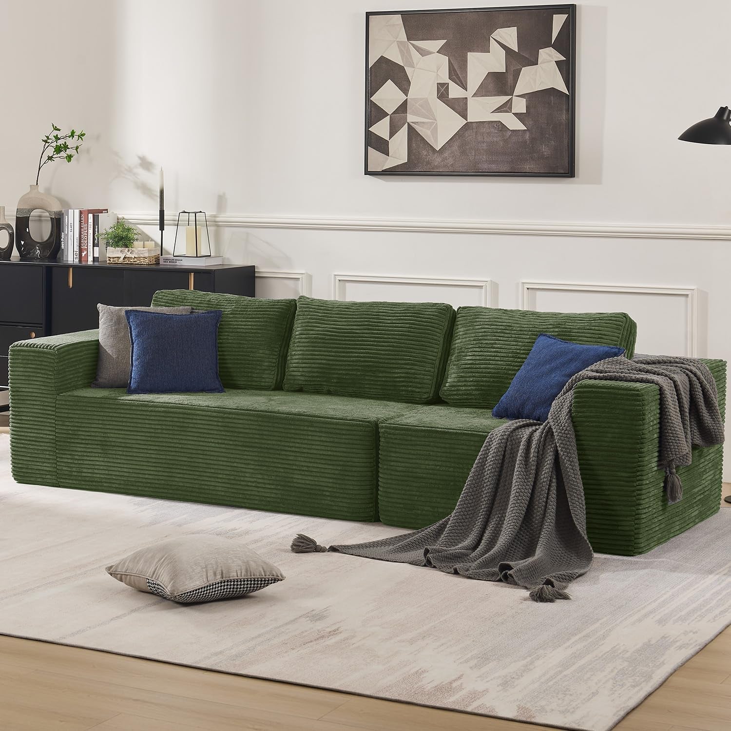 Green corduroy modular sofa with three back cushions and blue accent pillows in a styled living room