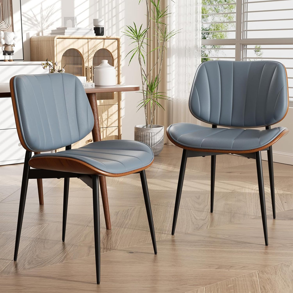 Two blue faux-leather dining chairs with walnut bentwood backs and tapered black legs in a sunlit dining space.