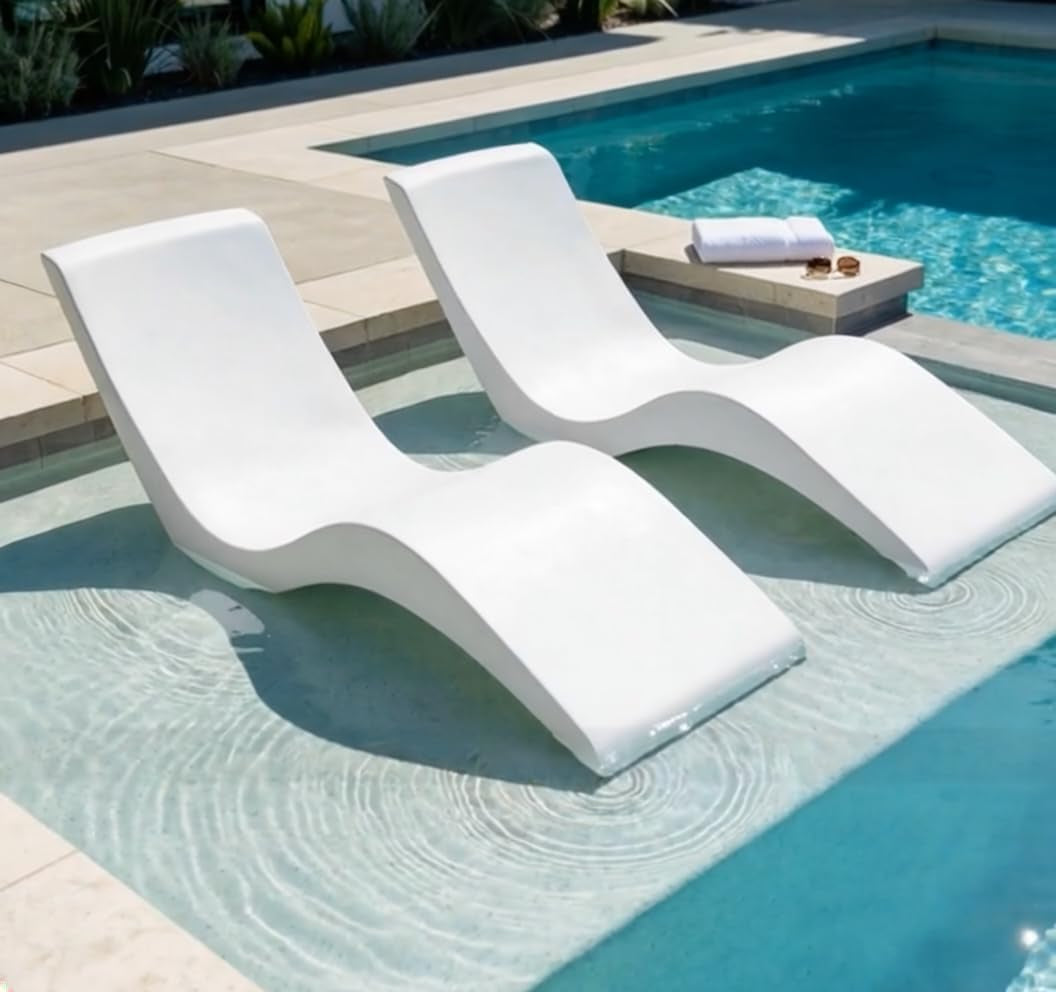 Pair of white resin ledge loungers set on a shallow pool sun shelf with visible water ripples, angled top view