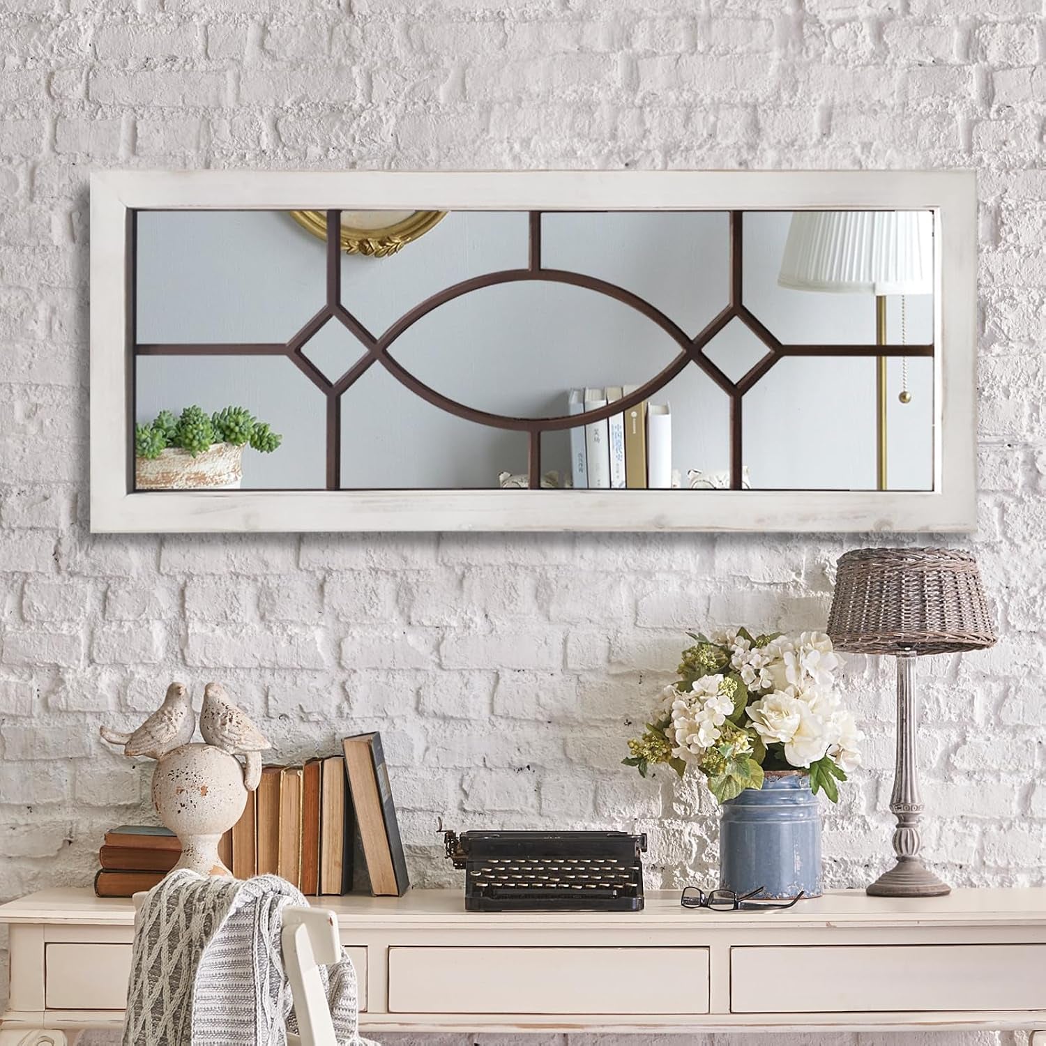 Horizontal windowpane mirror with distressed white frame mounted on a white brick wall above a desk vignette