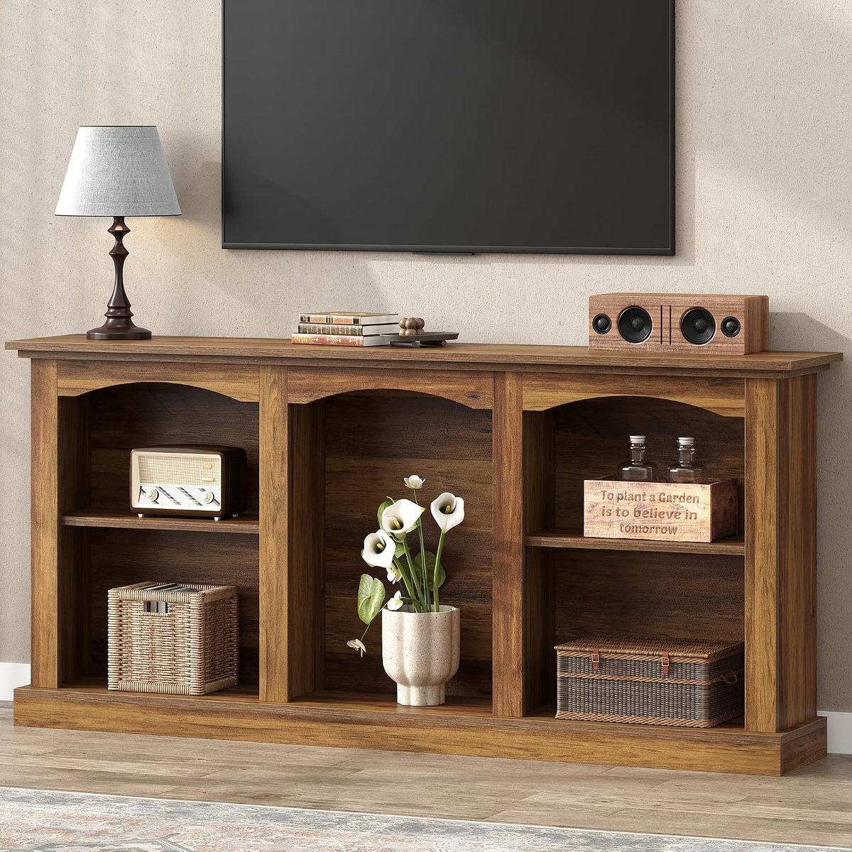 Console table beneath a wall-mounted TV with lamp, speaker, and decorative vases on the top.