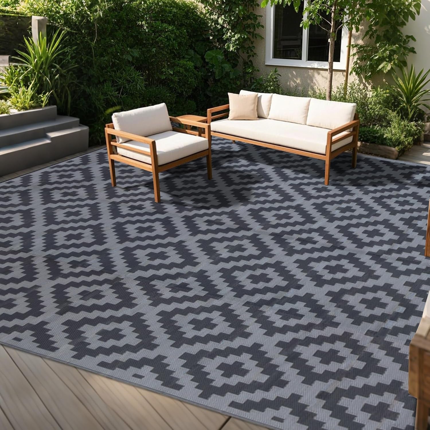 Outdoor deck scene with wood-framed seating on a gray rug featuring darker gray geometric motifs.