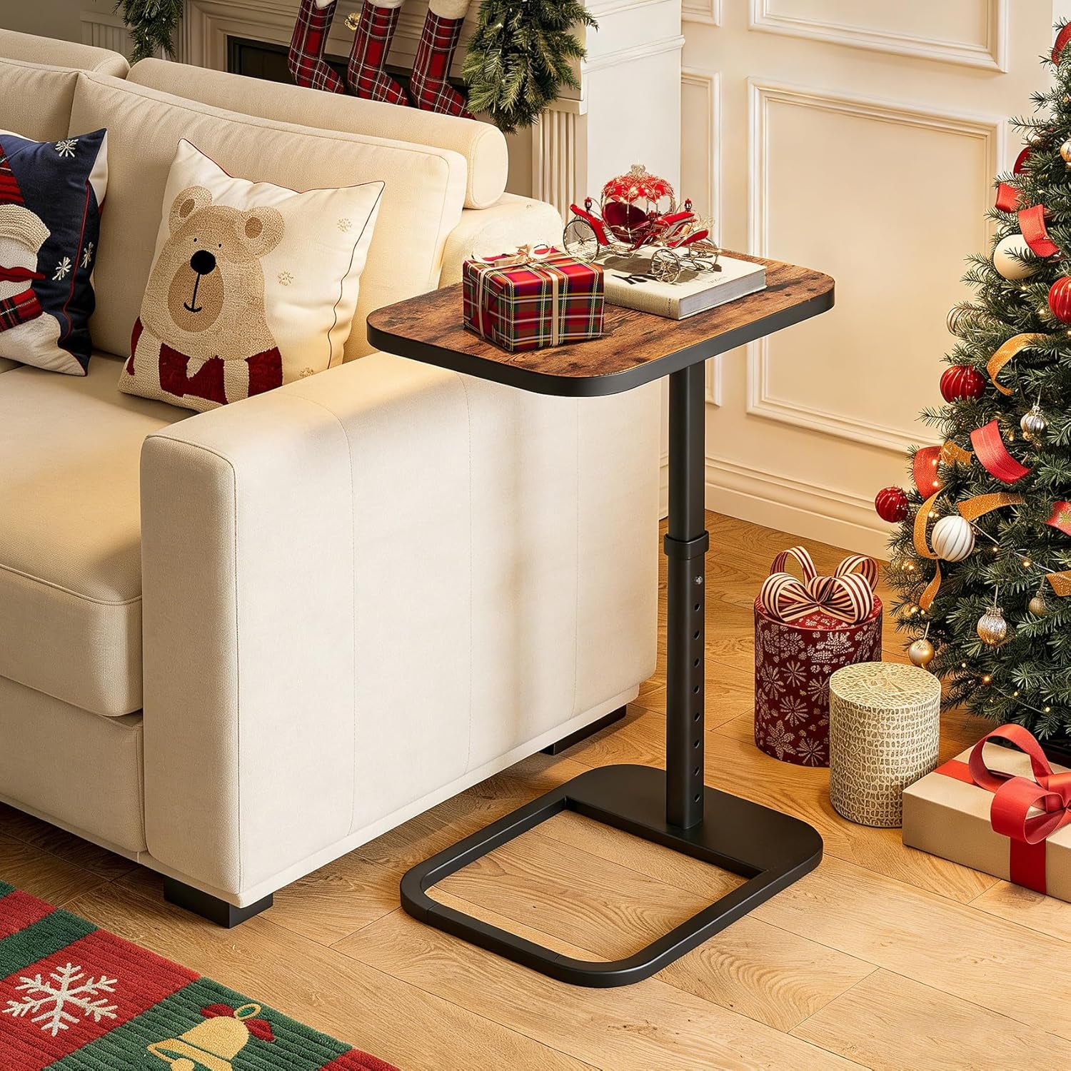 Snack table pulled over a sofa arm with holiday decorations and wrapped gifts beside a Christmas tree.