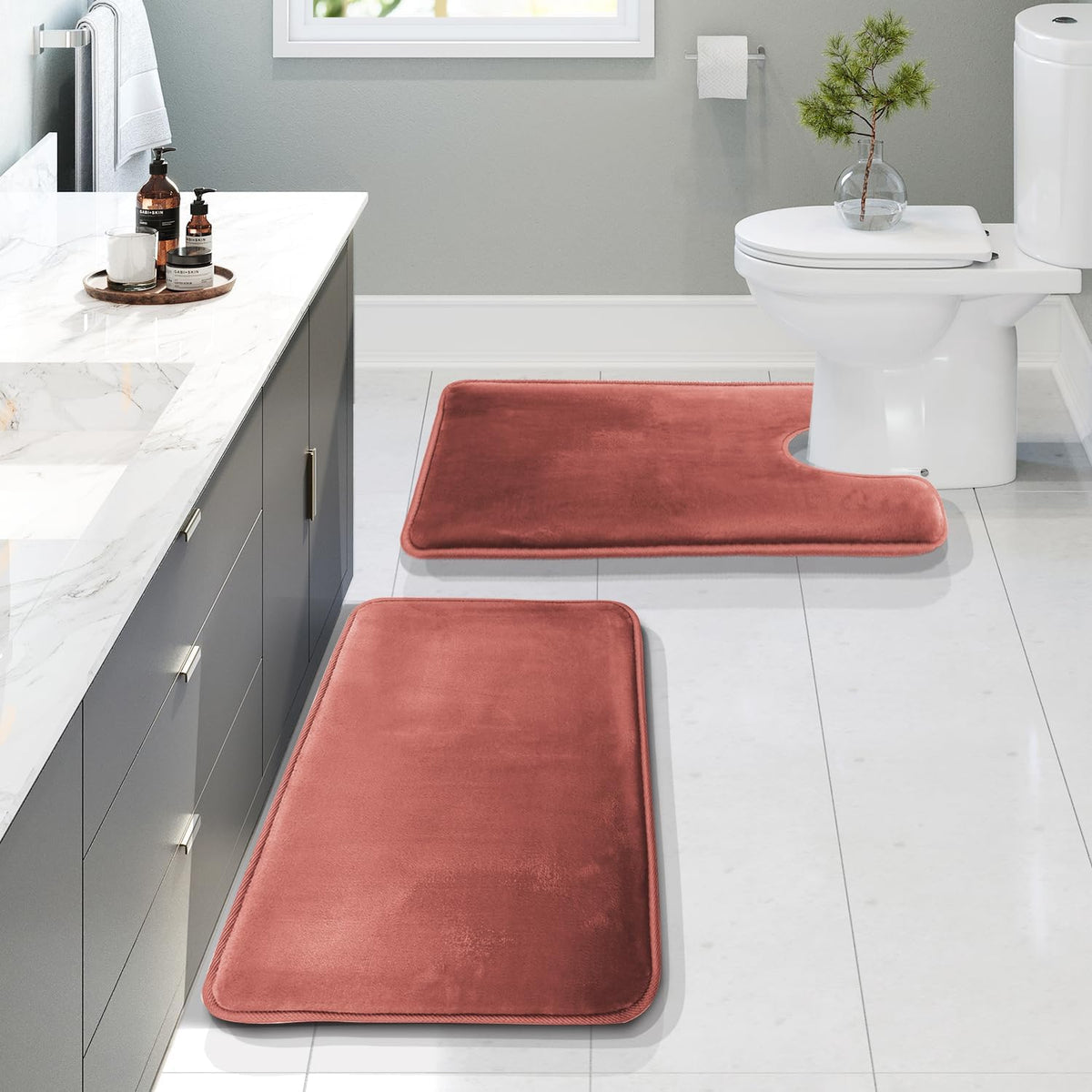 Bathroom with two rose-colored plush rugs, a rectangular runner and a U-shaped rug around the toilet