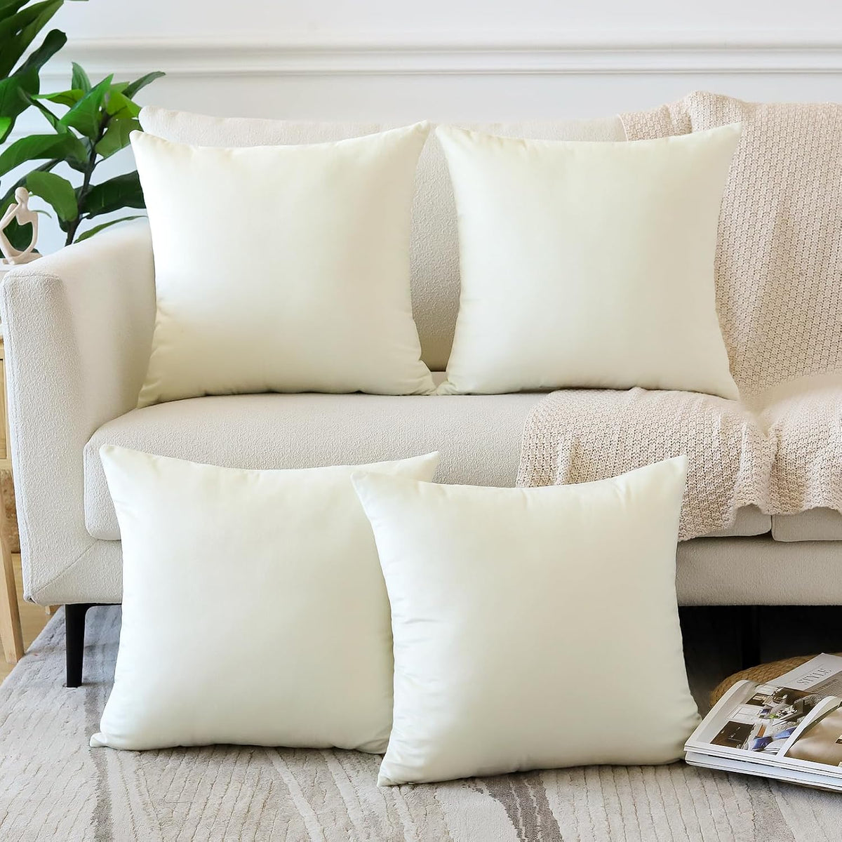 Four square cream throw pillow covers styled on a light sofa with a knitted throw.
