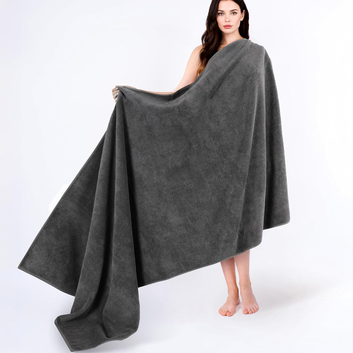 Woman holding a large dark gray towel wrapped around her, towel draping to the floor