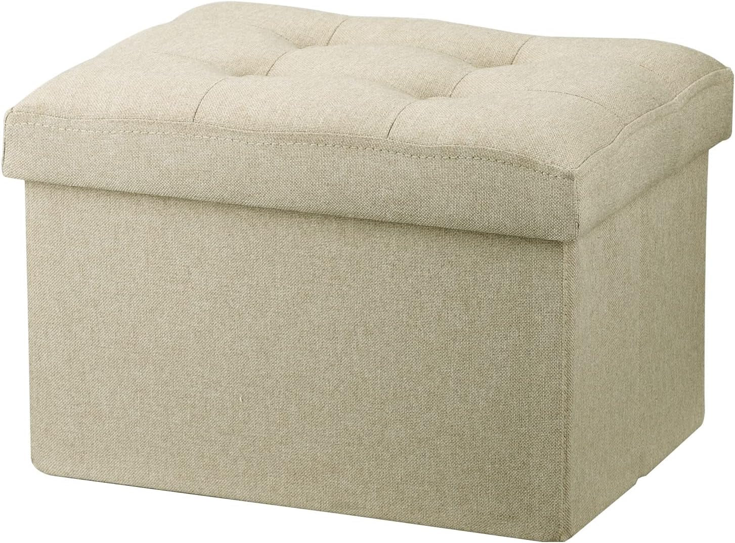 Three-quarter view of a square light beige fabric storage ottoman with tufted cushioned top.