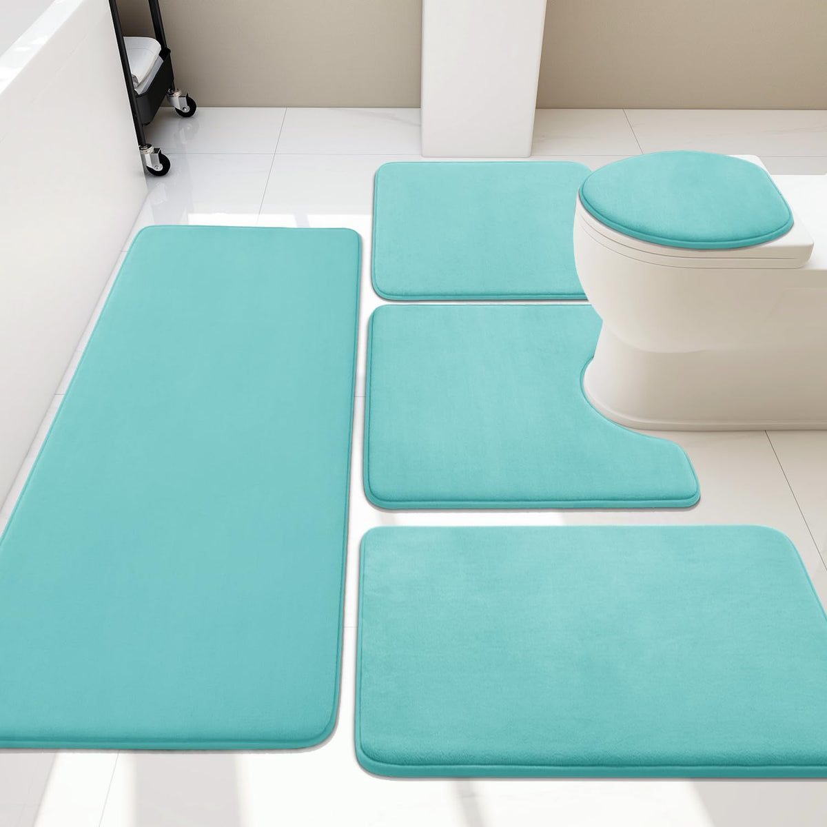Overhead shot of a turquoise four-piece bath rug set placed around a white toilet.