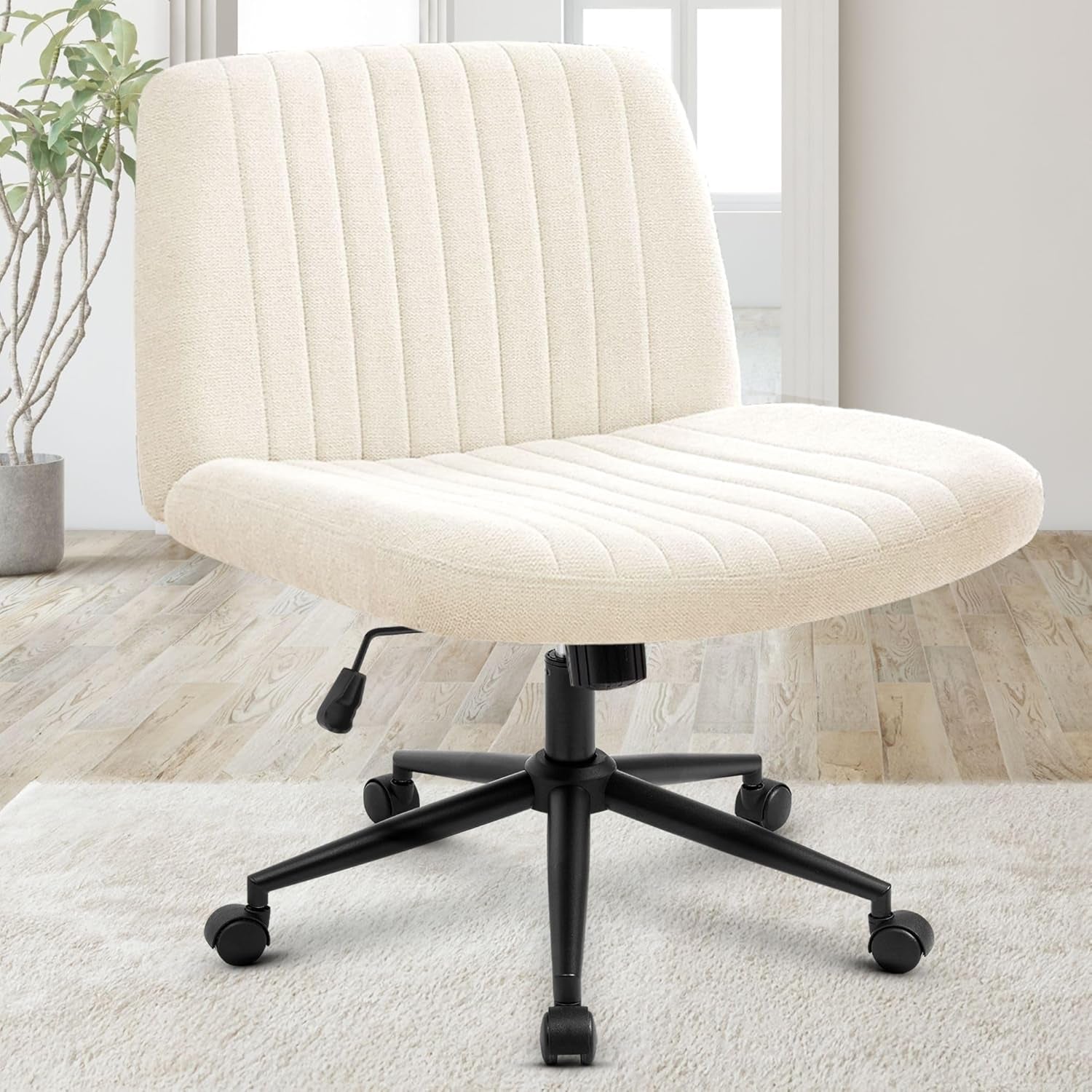Cream/off-white upholstered swivel desk chair with vertical channel stitching and black star base on light wood floor.