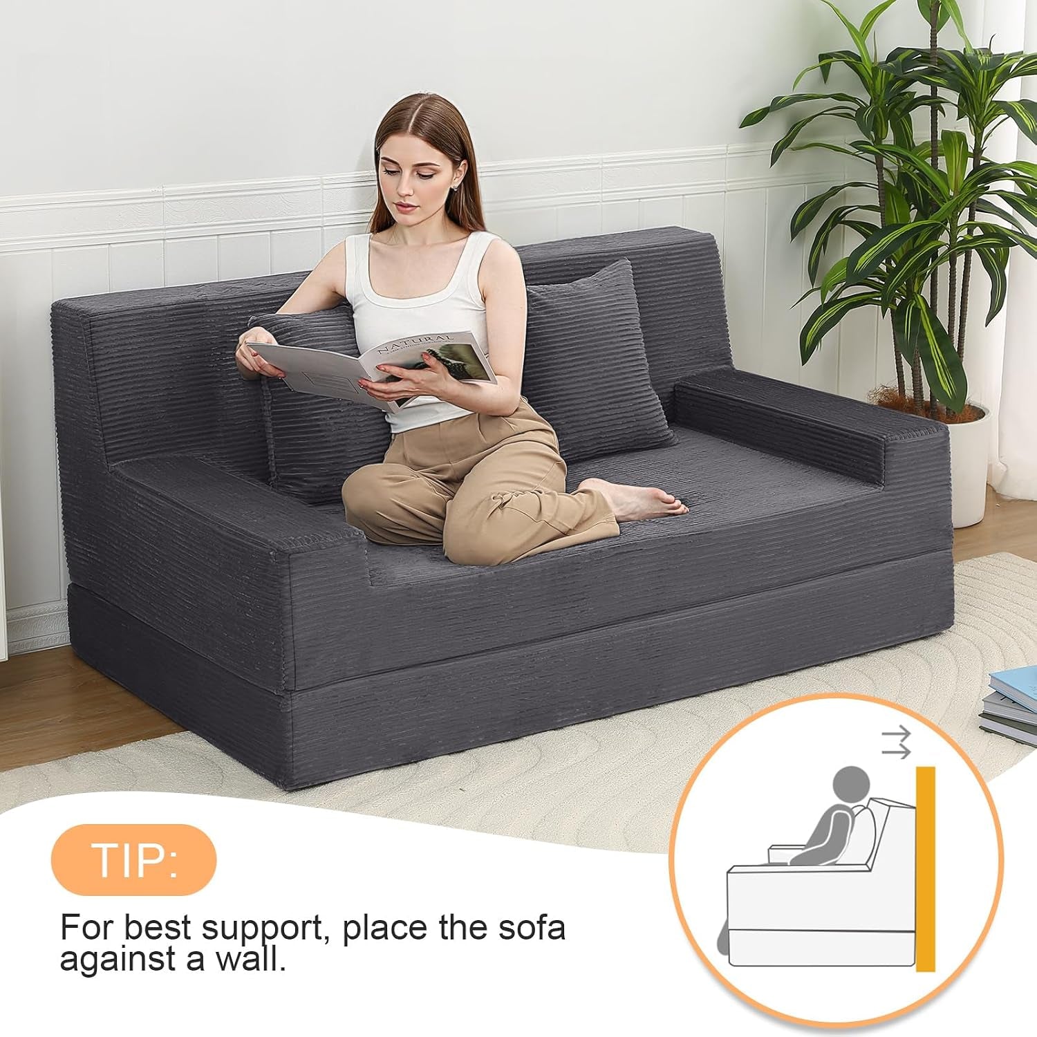 Dark grey loveseat in use with a person reading while placed against a wall