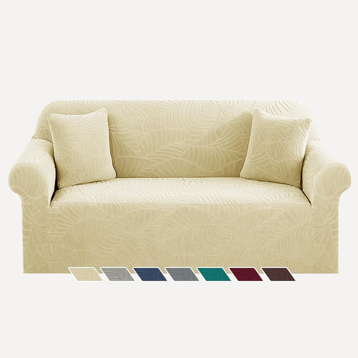 Front view of a three-seat sofa draped in a cream-beige jacquard slipcover with two matching pillows.
